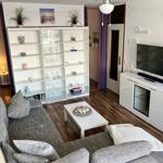 Wohnzimmer mit Sofa, Couchtisch und TV-Möbel. Hintergrund: Bücherregal und Tür.
