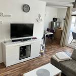 Wohnzimmer mit TV, Sofa und Blick auf Balkon