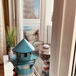 Blauer Leuchtturm auf Fensterbank mit Blick auf Strand und Gebäude