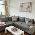 Ein Wohnzimmer mit grauem Sofa, weißem Tisch und Wandbild.