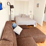 Schlafzimmer mit Bett, Schrank und Sofa. Holzboden und weiße Wände.