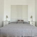 Schlafzimmer mit Bett, Nachttischen und Schrank. Kissen mit Ankerplatz Aufdruck.
