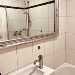 Badezimmer mit Waschbecken, Spiegel und Badewanne