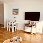 Wohnzimmer mit Esstisch, Fernseher und Kleiderschrank.