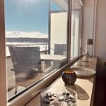 Großes Fenster mit Blick auf Hafen und Terrasse mit Stuhl und Tisch.