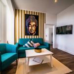 Wohnzimmer mit türkisfarbenem Sofa und Sessel, Wandbild Buddha und Flachbildschirm.