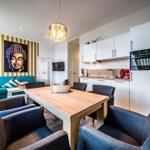 Essbereich mit Holztisch und Stühlen, Küchenzeile und Buddha-Bild an der Wand.