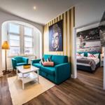 Wohnzimmer mit Sofa, Sessel und Bett im Hintergrund.