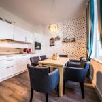 Küche mit Essbereich, Holztisch, grauen Stühlen und goldpunktiertem Wandpaneel.