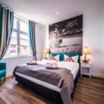 Schlafzimmer mit Bett, Fenster, TV und Wandbild.