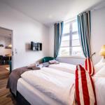 Zwei Betten mit weißen Bettwäsche, Fenster mit Streifen Vorhängen, Wandbild und Lampe.