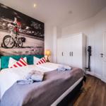 Schlafzimmer mit Bett, Kleiderschrank und Wandbild mit Fahrrad