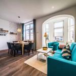 Wohn- und Essbereich mit Sofa, Tisch und Fenstern.