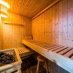 Holzsauna mit Sitzbänken und Heizung. Warmes Licht und hölzernes Ambiente.