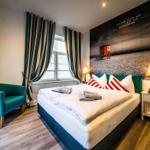 Schlafzimmer mit Bett, Sessel und Fenster mit Vorhängen.