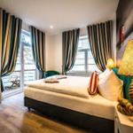 Schlafzimmer mit Bett, TV und Balkon. Vorhänge und Lampe sind sichtbar.