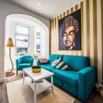 Ein Wohnzimmer mit türkisfarbenem Sofa, Buddha-Bild und Streifenwand.