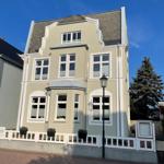 Ein dreigeschossiges Haus mit hellen Fenstern und weißer Fassadendekoration.