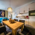 Essbereich mit Holztisch, Küchenzeile und Buddha-Bild an der Wand.