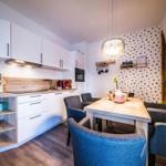 Küche mit Essbereich, Holztisch und Stühlen, weiße Schränke und Holzoberfläche.