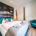 Schlafzimmer mit Bett, Sessel und Wandbild mit Leuchtturm.