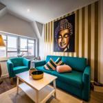 Ein Wohnzimmer mit türkisfarbenem Sofa, einem Buddha-Bild und gestreifter Wand.