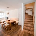 Essbereich mit Holztisch, Stühlen und Treppe zur oberen Etage.