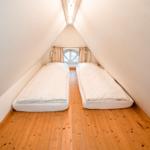 Zwei Betten in einem Dachzimmer mit Holzboden und Fenster