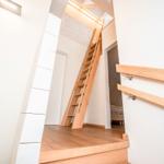 Holztreppe führt zu einer oberen Etage mit Schlafzimmer. Moderne Beleuchtung und Holzboden.