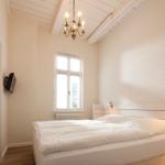 Schlafzimmer mit Bett, Fenster und Kronleuchter.