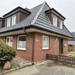 Einfamilienhaus mit rotem Backstein, Dachgauben und kleinem Vorgarten.