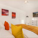 Schlafzimmer mit Bett, Wandbildern und Schrank.