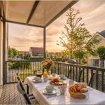 Terrasse mit Tisch, Stühlen und Frühstück. Blick auf Straße und Gebäude.
