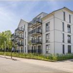 Modernes Mehrfamilienhaus mit Balkonen und grüner Umgebung.