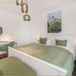Schlafzimmer mit Bett, Schreibtisch und Wandbild.