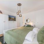 Schlafzimmer mit Bett, Kleiderschrank, TV und Schreibtisch.