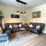 Wohnzimmer mit zwei Sofas, Sitzbank und Couchtisch. Küche im Hintergrund.