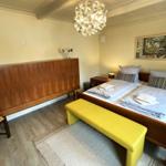 Schlafzimmer mit Doppelbett, Holzschrank und gelber Sitzbank.