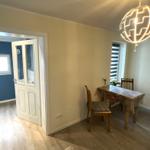 Esszimmer mit Tisch, Stühlen und Deckenleuchte. Tür führt in Schlafzimmer.