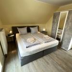 Schlafzimmer mit Doppelbett, Kleiderschrank und Nachttischen.