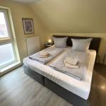 Schlafzimmer mit Doppelbett, Fenster und Nachttischen.