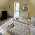 Schlafzimmer mit Doppelbett, Fenster und Sitzgelegenheit.