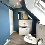 Badezimmer mit Dachschrägen, Waschbecken, Spiegel und Toilette.