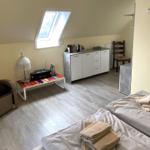 Zimmer mit Dachschrägen, zwei Betten, Schrank und Sitzgelegenheit.