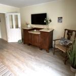 Wohnzimmer mit Sofa, TV-Schrank und Holzstuhl. Holzfußboden und helle Wände.