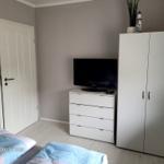 Schlafzimmer mit Bett, Kleiderschrank und Fernseher auf Schrank.