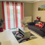 Wohnzimmer mit Sofa, Couchtisch und roten Vorhängen.