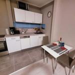 Küche mit Essbereich, weißen Schränken und Tisch mit zwei Stühlen.