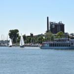 Schiffsanleger mit Segelbooten und Dampfschiff auf ruhigem Wasser.