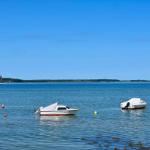Zwei Motorboote und ein Segelboot auf ruhigem Wasser unter blauem Himmel.
